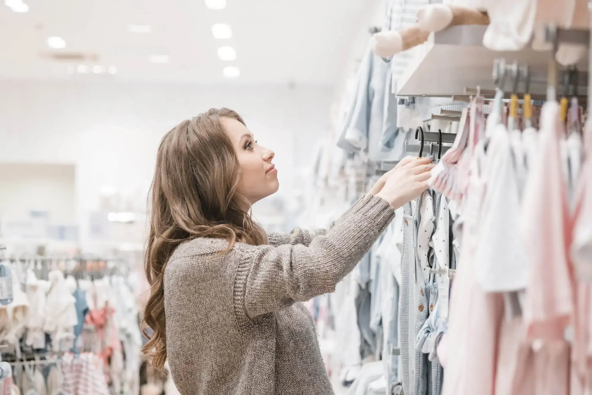 Mujer en una tienda de ropa para bebés, viendo la mercancía