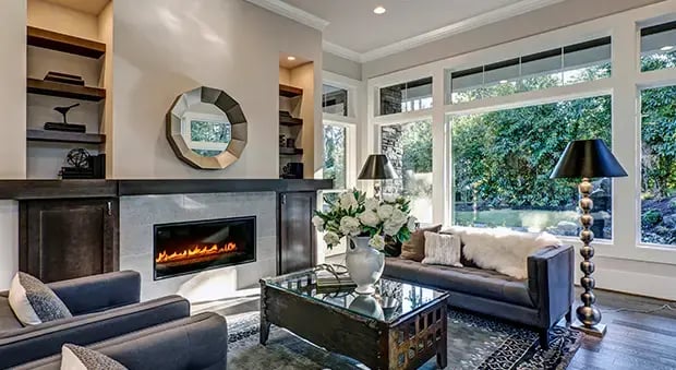 Sala de estar con sillones, reloj de pared, grandes ventanas y una mesa de centro