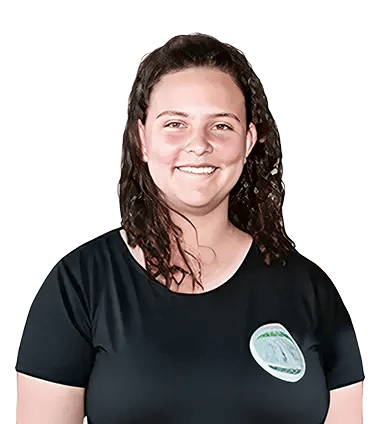 Mujer de pie con camiseta negra, sonriendo, con el cabello rizado y un gafete adherido a la prenda.