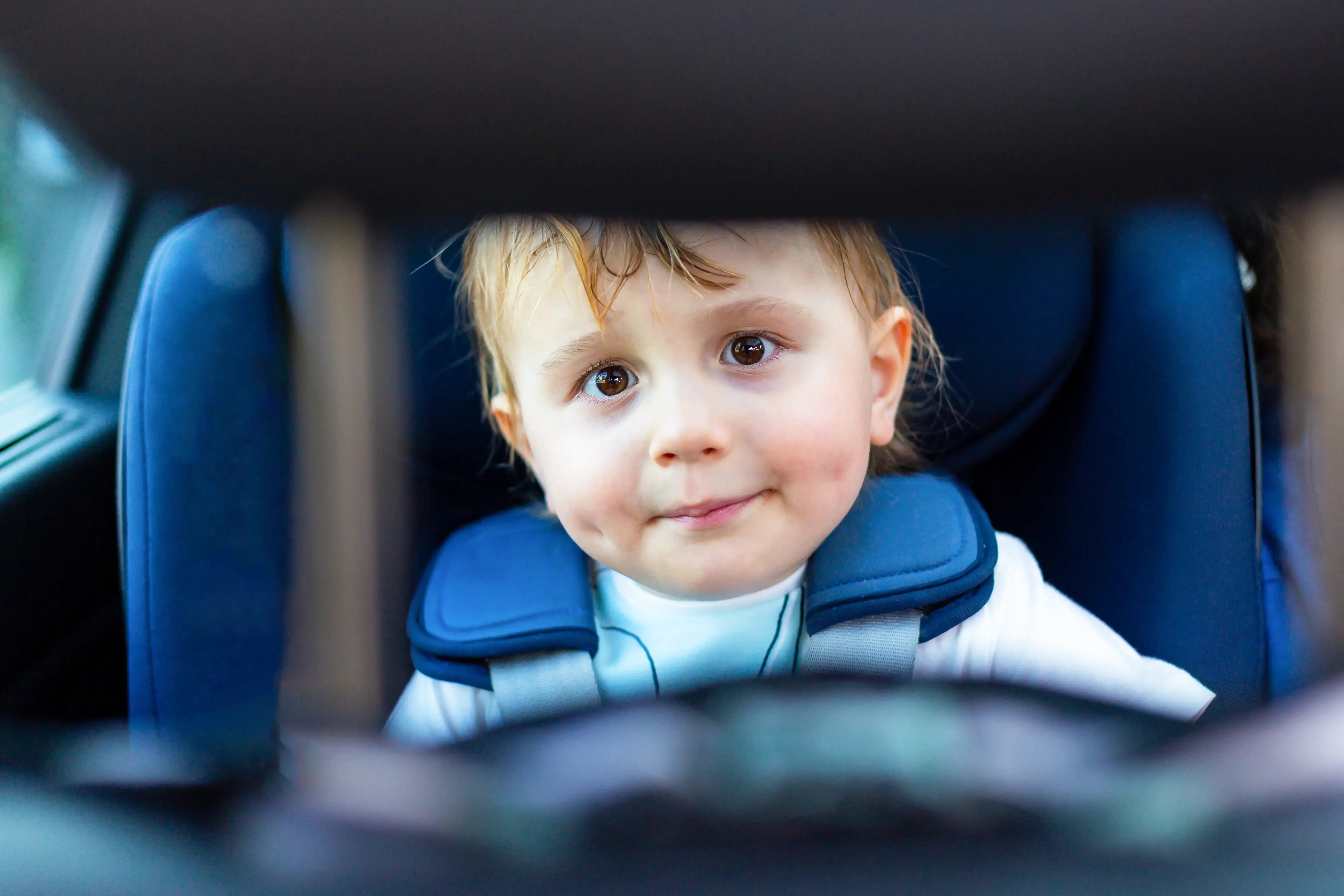 Niño pequeño sentado en una silla de seguridad dentro de un automóvil.