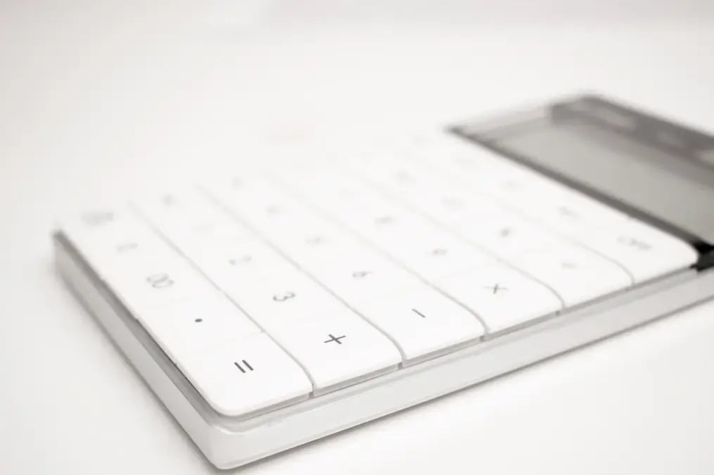Calculadora blanca sobre una superficie clara en primer plano.