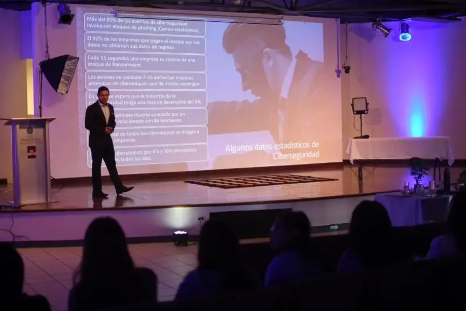 Ponente dando una charla sobre ciberseguridad frente a una pantalla con estadísticas.