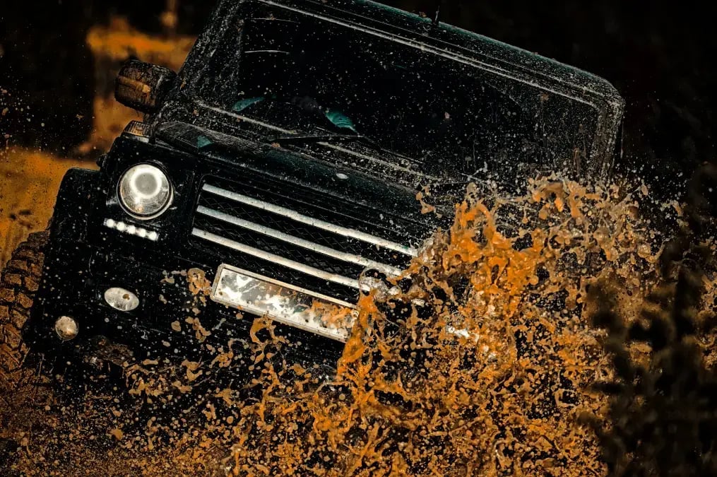 Jeep negro levantando una ola de barro en un camino off road
