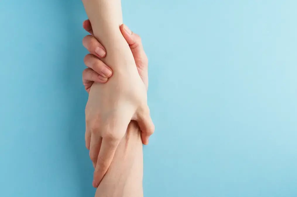 Mano sujetando firmemente a otra en señal de apoyo y solidaridad.