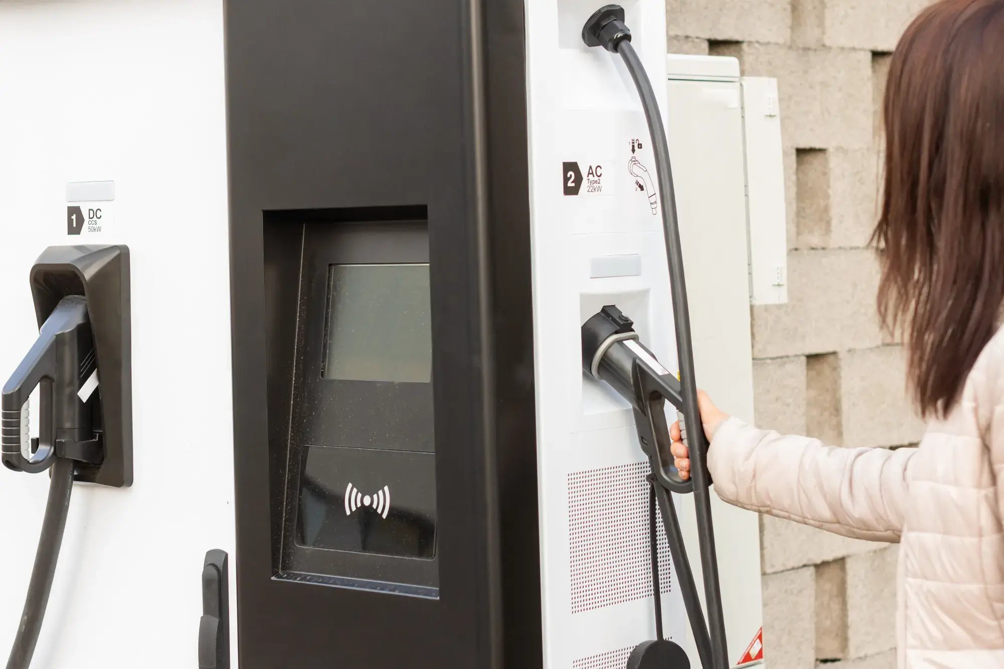 Persona conectando un automóvil en estación de carga para vehículos eléctricos.