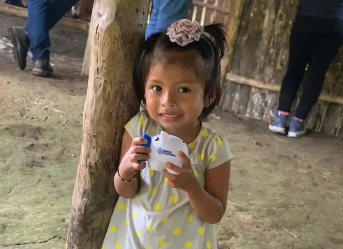 Niña sonriente sostiene una alcancía del Banco Nacional de Costa Rica como símbolo del hábito del ahorro