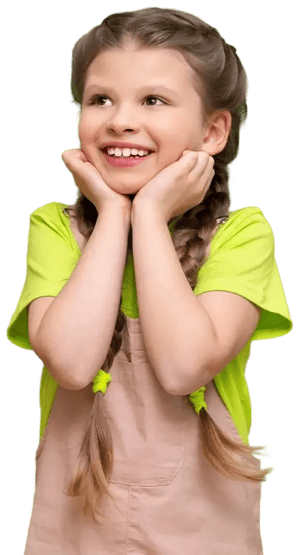 Niña sonriendo con expresión de ilusión mientras sostiene su rostro con ambas manos, vestida con camiseta verde y overol claro.