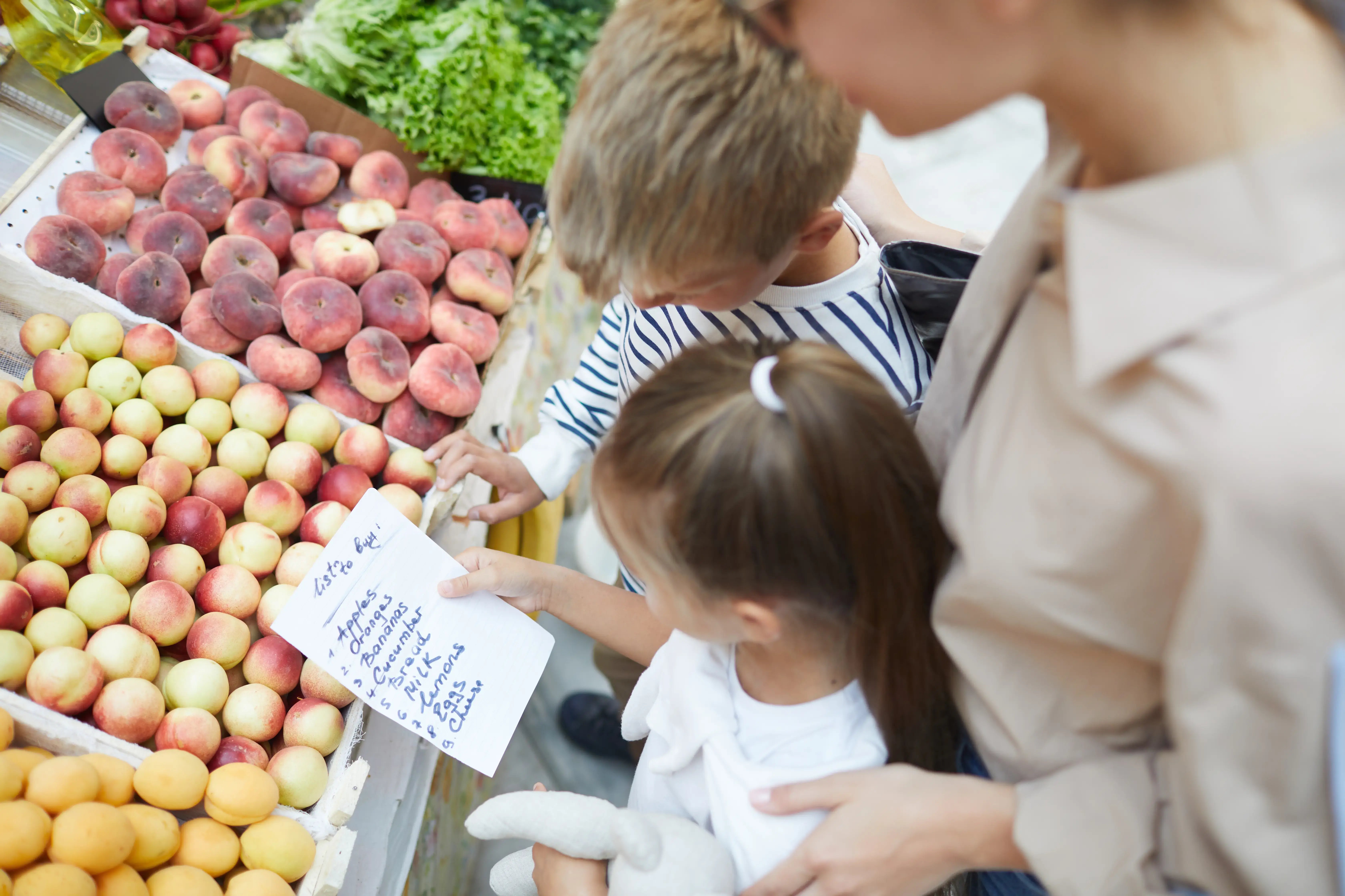 Niños con lista de compras en un mercado de frutas y verduras