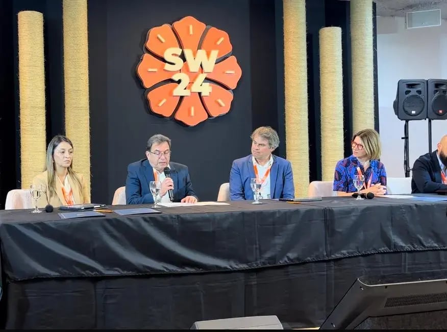 Panel de conferencistas hablando frente al logotipo SW24 durante un evento empresarial