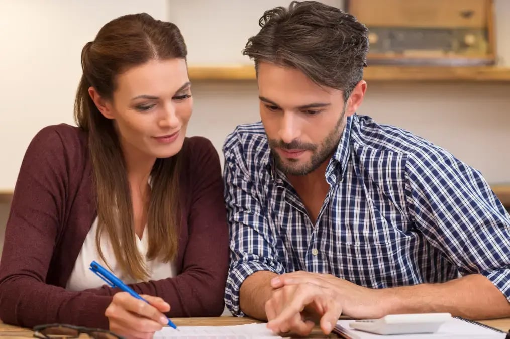Pareja revisando documentos y tomando notas en una mesa.