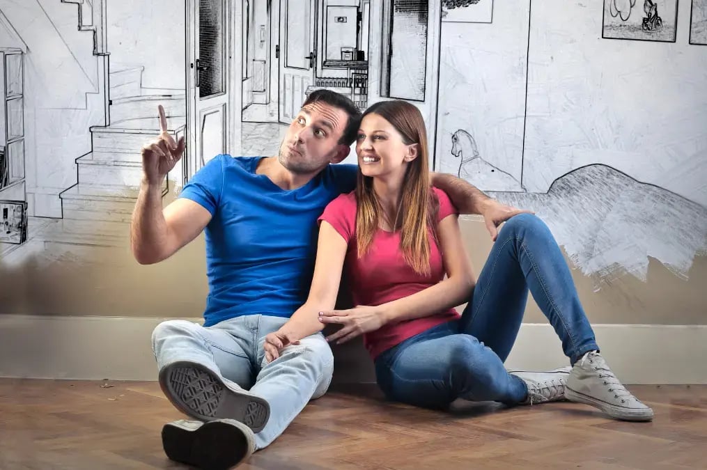 Pareja sentada en el piso imaginando la decoración de su nuevo hogar
