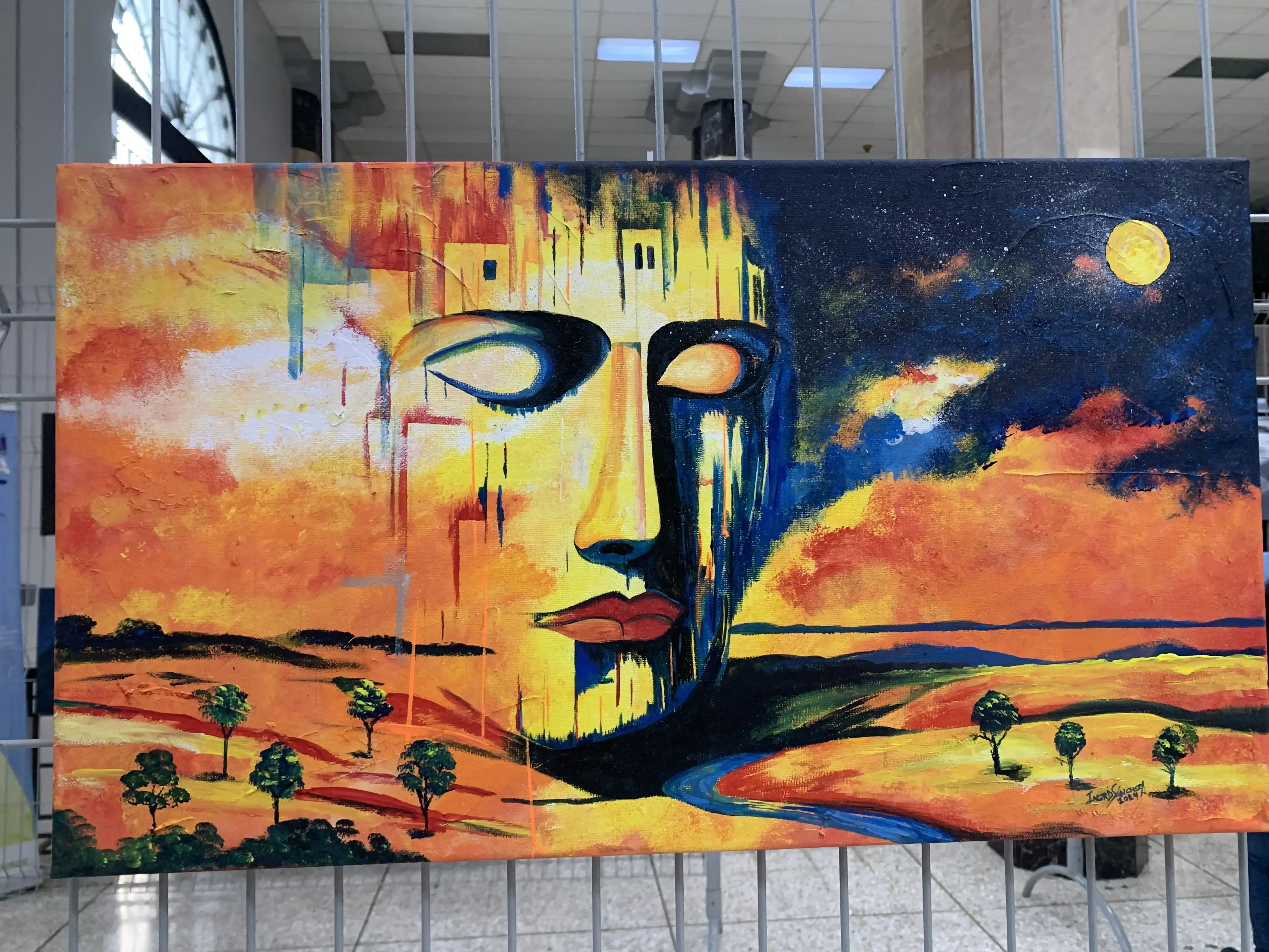 Pintura de paisaje colorido con un gran rostro humanoide fusionado con el cielo y la tierra, en tonos cálidos de naranja, amarillo y azul, bajo una luna brillante.