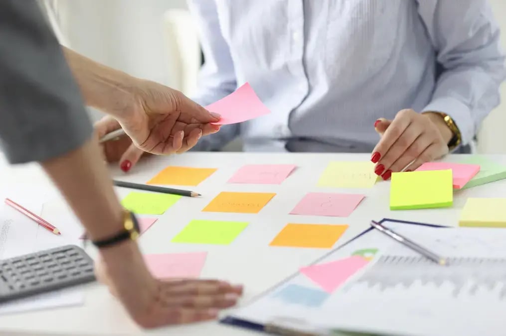 Personas organizando ideas con notas adhesivas de colores en reunión de planificación financiera BNCR.
