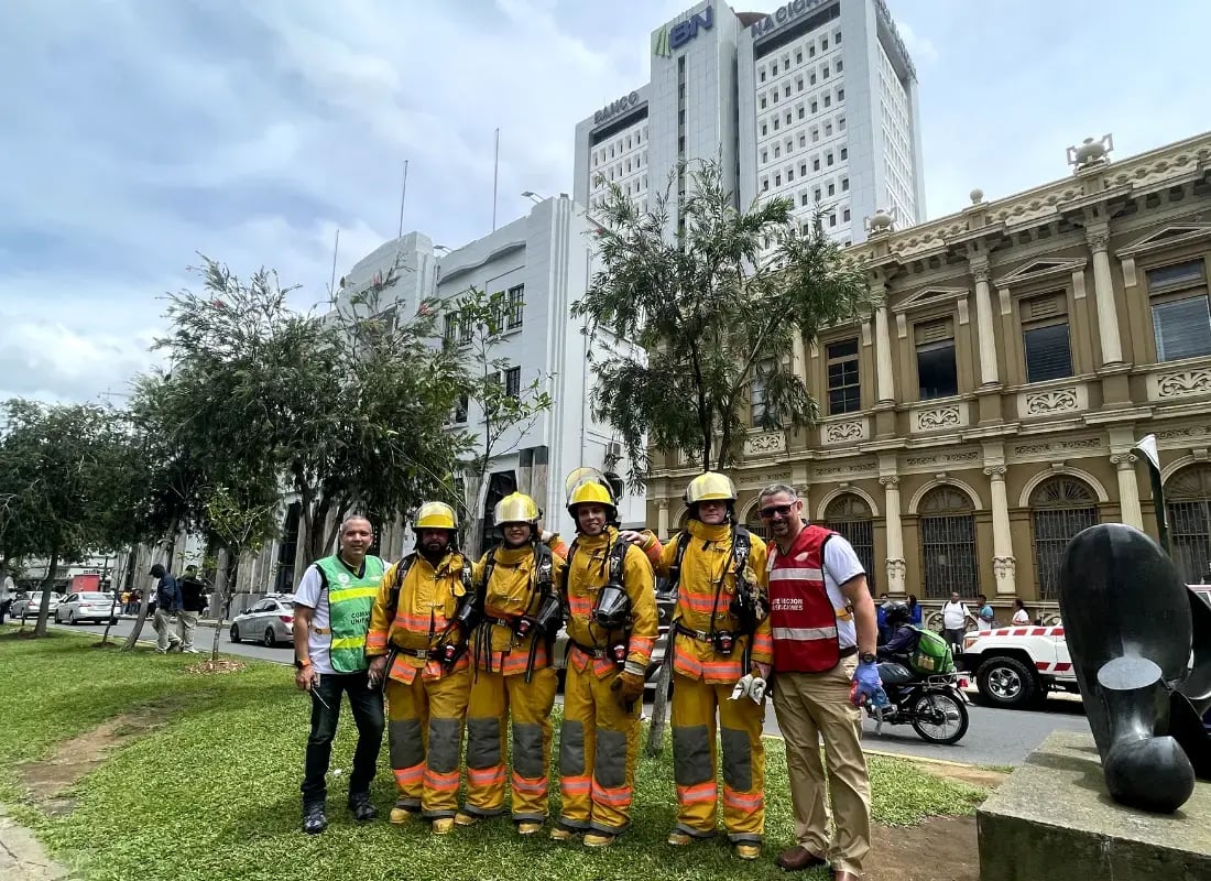 Bomberos y personal de emergencia posan frente al edificio del Banco Nacional en San José tras un simulacro.