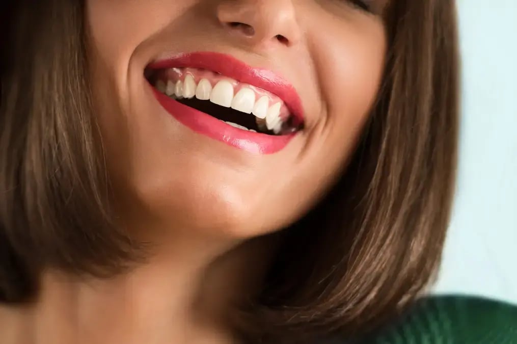 Sonrisa de mujer mostrando dientes blancos y labios pintados de rojo