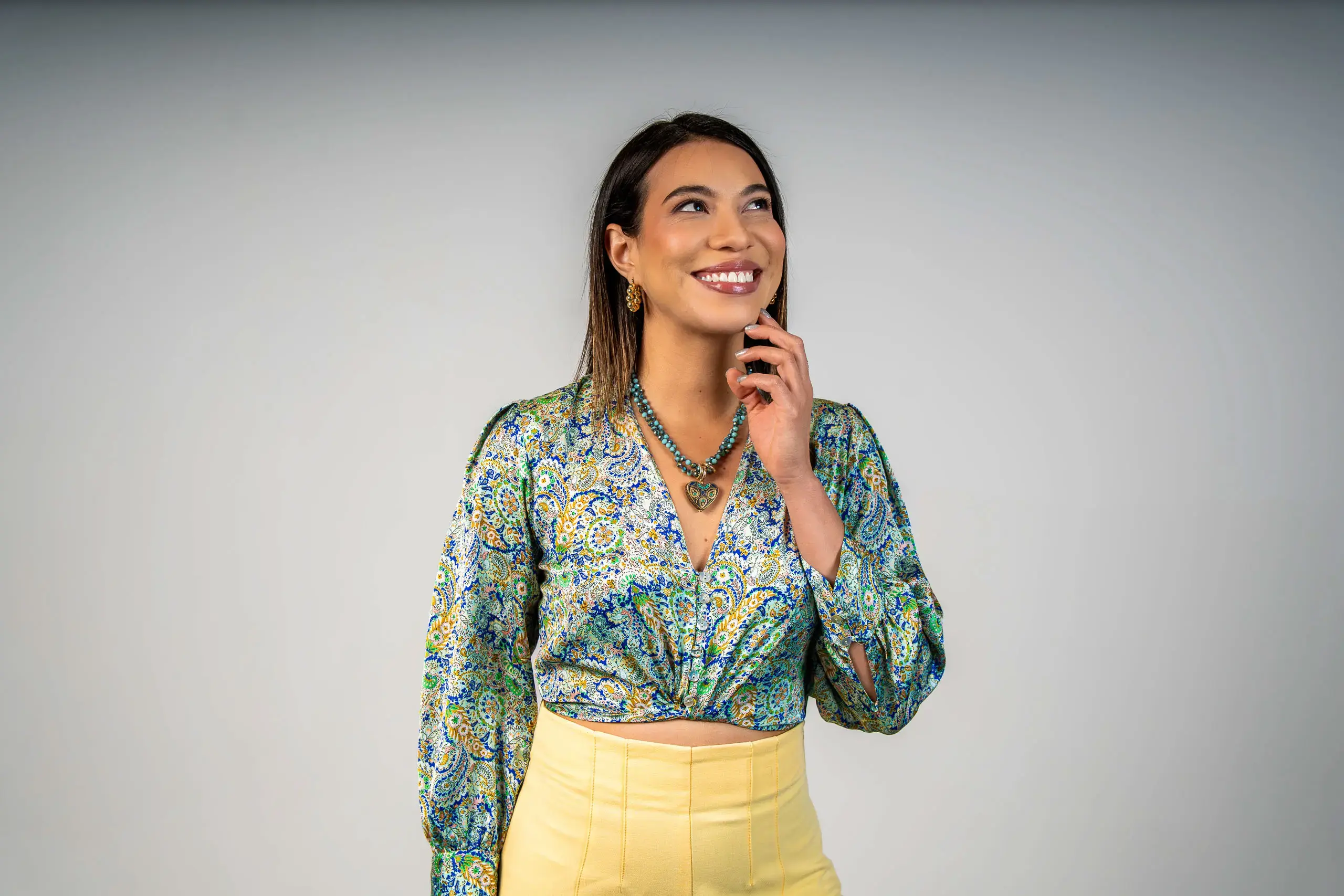 Mujer sonriendo mientras mira hacia arriba sobre un fondo claro.