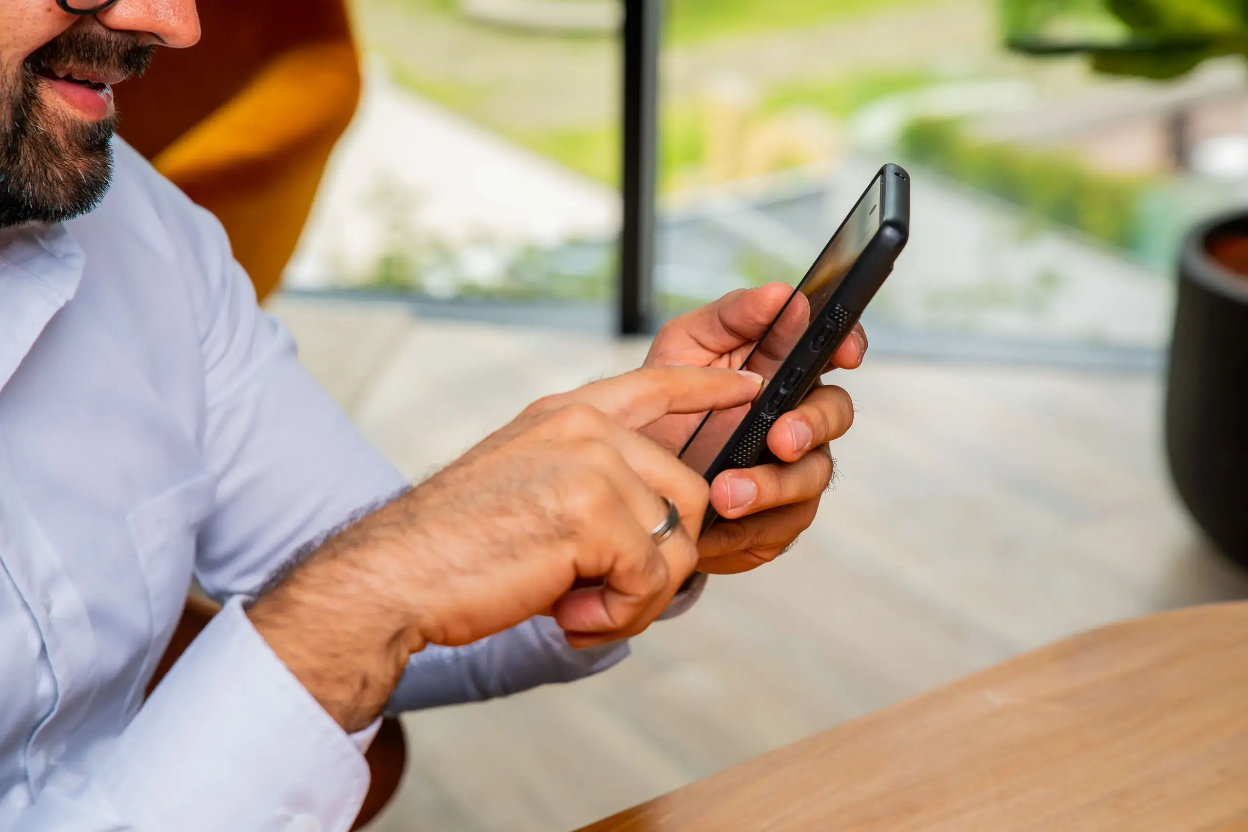 Manos de un hombre utilizando un teléfono móvil mientras navega en la pantalla.