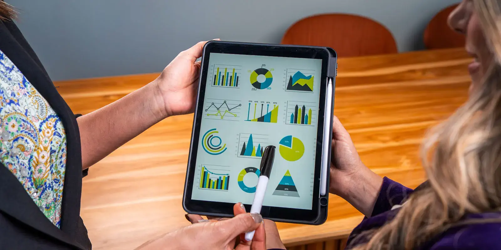 Personas sosteniendo una tableta que muestra gráficas y diagramas de colores.