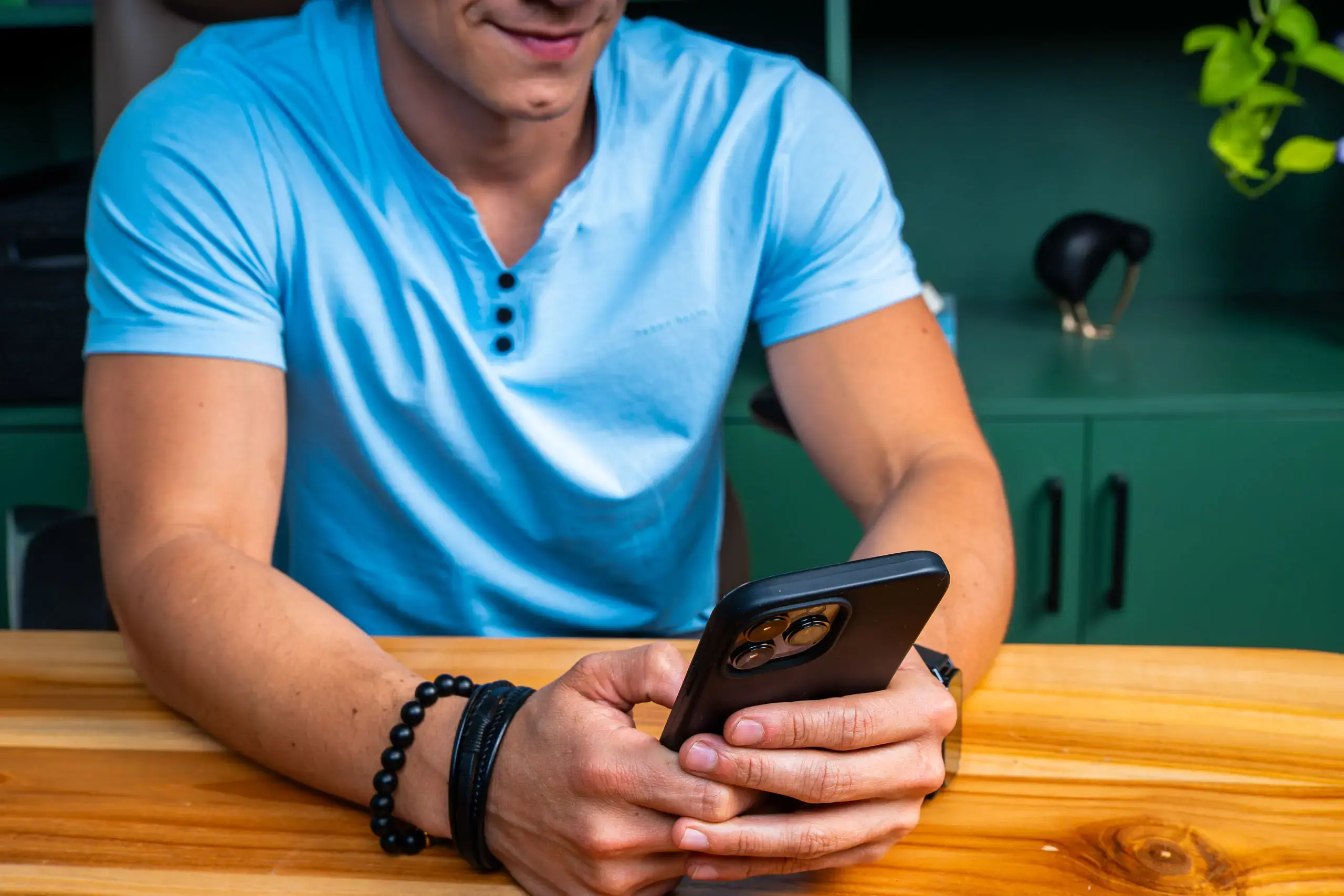 Persona sujetando un teléfono móvil sobre una mesa de madera.