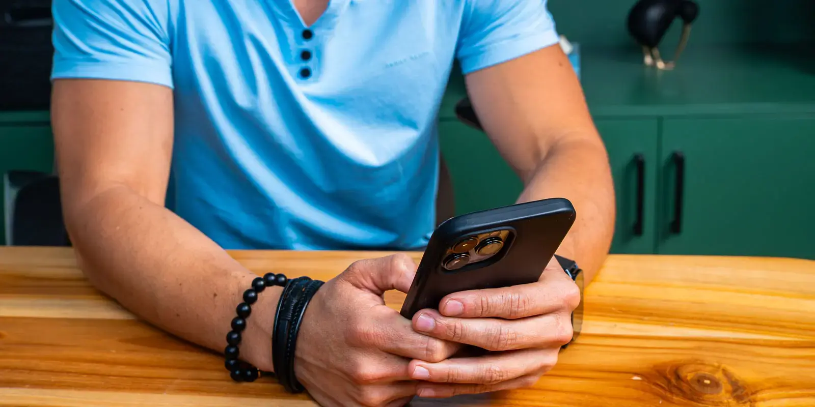 Persona sujetando un teléfono móvil sobre una mesa de madera.