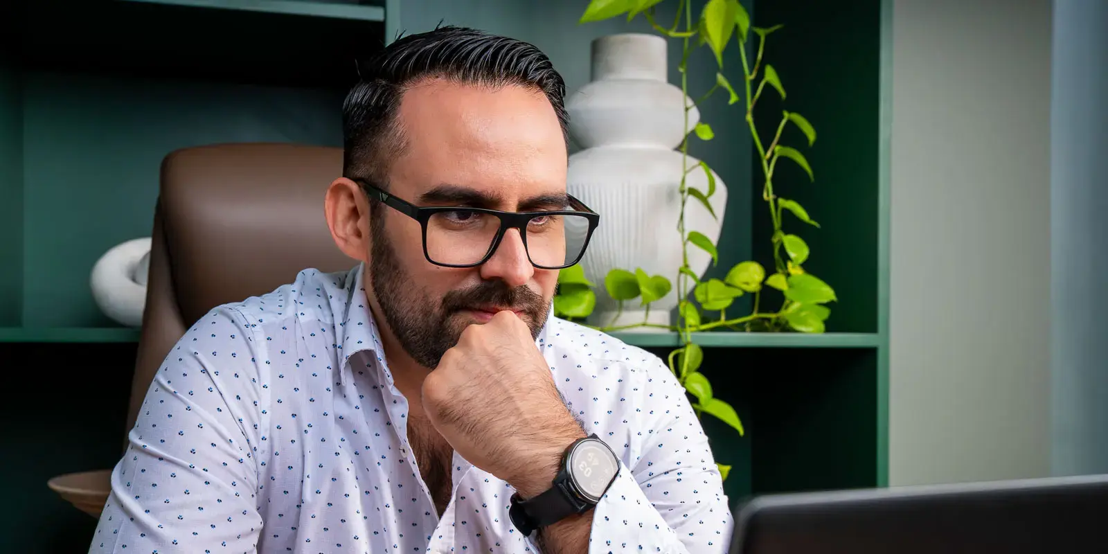 Hombre con gafas trabajando concentrado frente a una computadora.