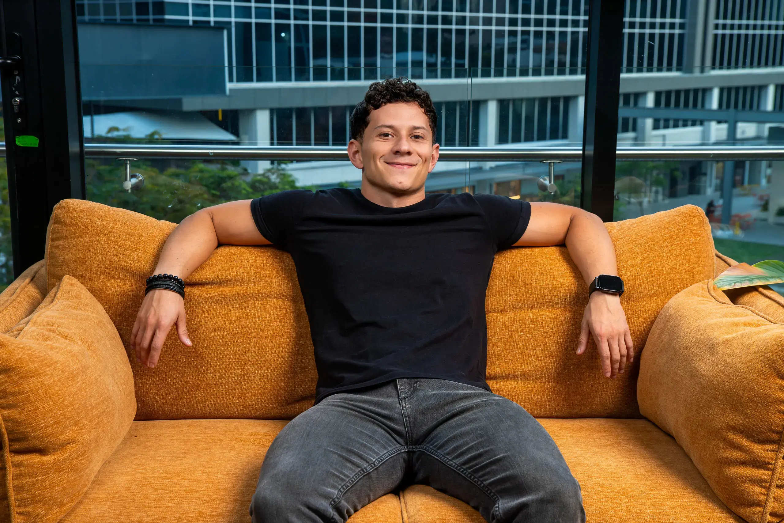 Persona sentada en un sillón naranja con los brazos extendidos sobre los reposabrazos.