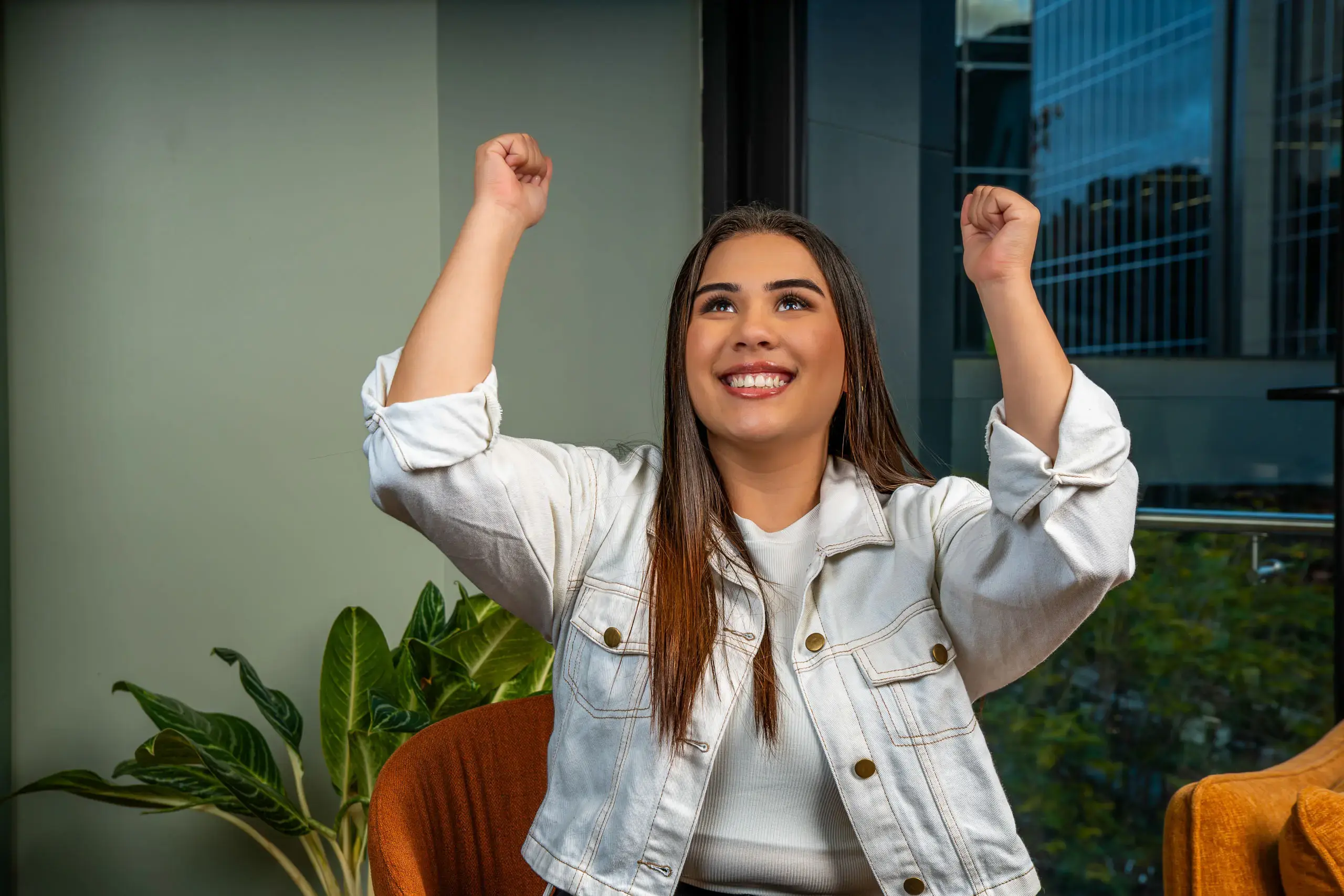 Mujer levantando los brazos con gesto de alegría mientras sonríe.