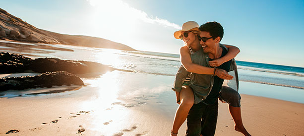 Pareja feliz caminando por la playa mientras el hombre carga a la mujer en la espalda.-1609240000007148