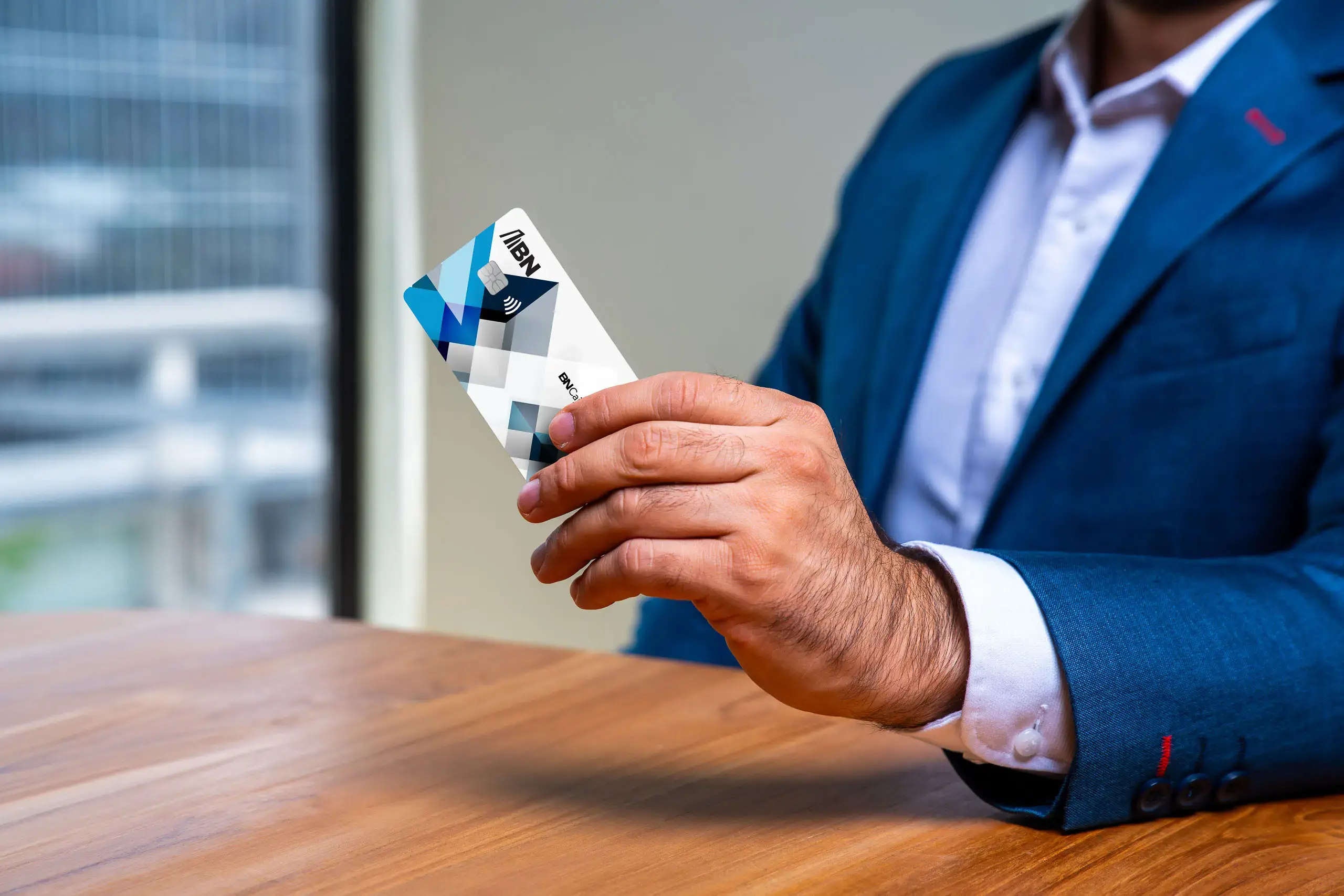 Hombre sosteniendo una tarjeta BN Caja Chica sobre un escritorio.