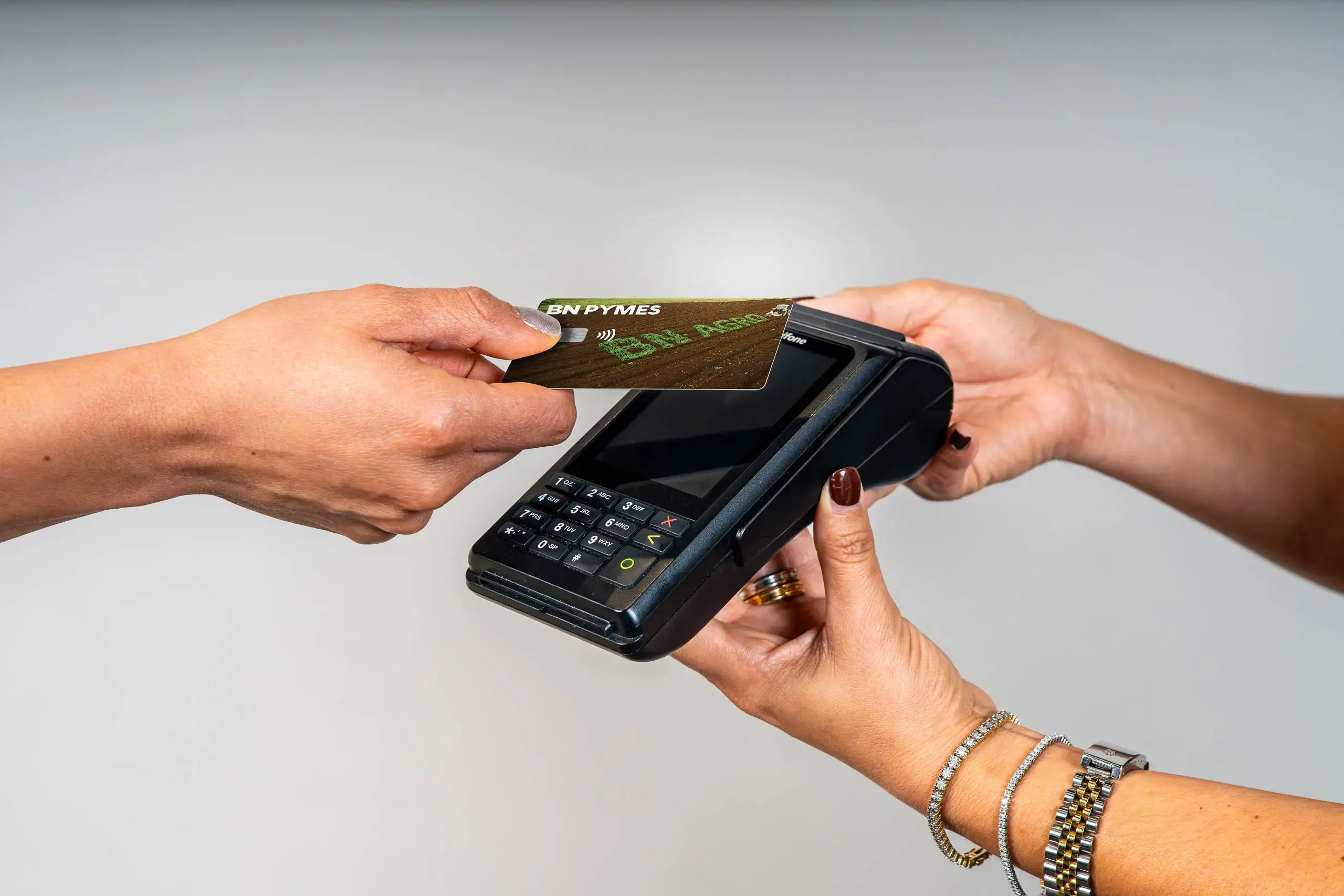 Manos realizando un pago acercando una tarjeta BN Pymes a un datáfono.