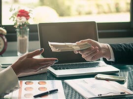 Intercambio de dinero en efectivo entre dos personas en un entorno de oficina.