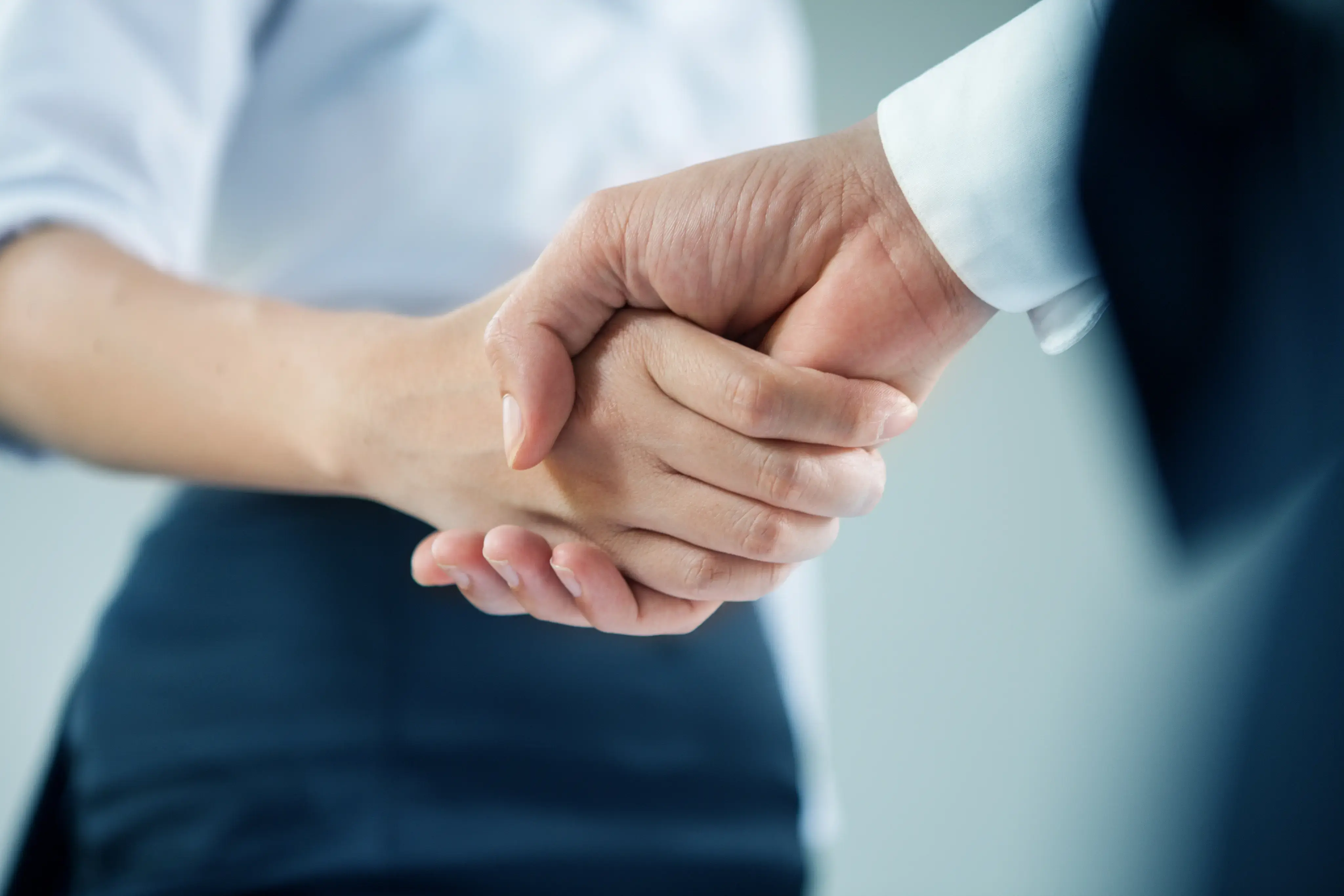 Primer plano de dos personas estrechando manos en un entorno profesional.