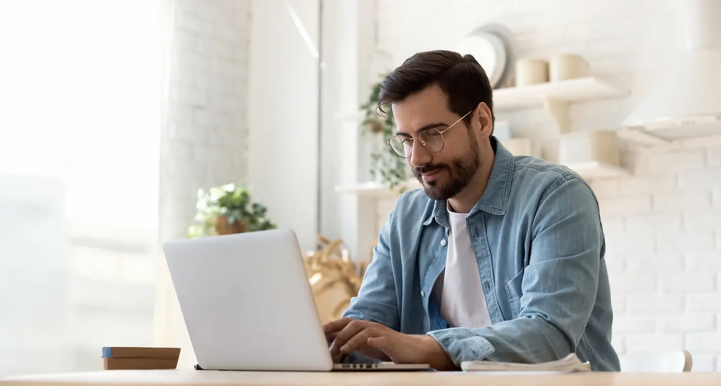 Hombre usando una computadora portátil en un espacio interior iluminado.