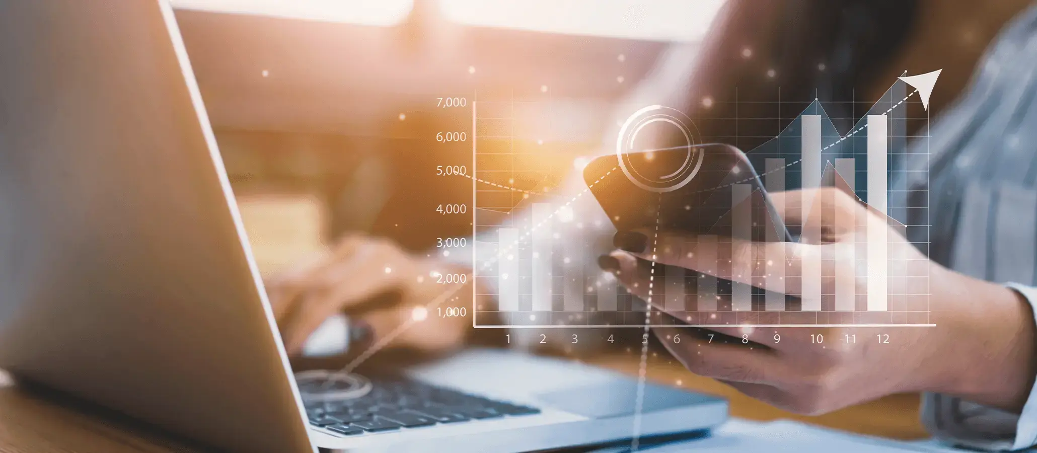 Persona utilizando una laptop y un teléfono móvil con gráficos digitales de crecimiento financiero superpuestos.