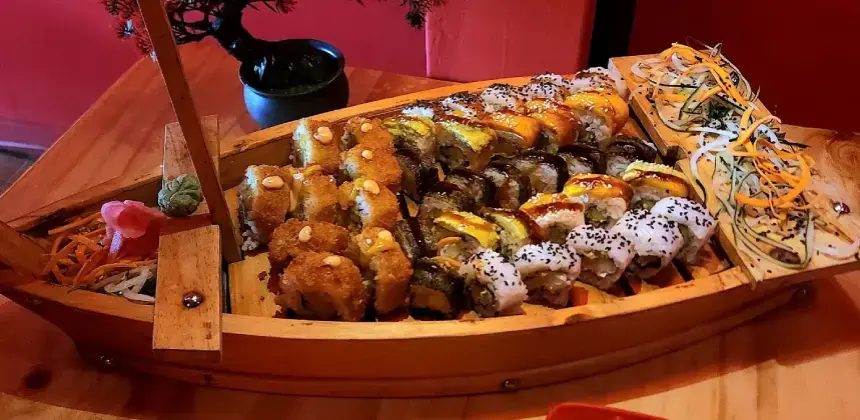 Barco de madera servido con variedad de sushi y acompañamientos.