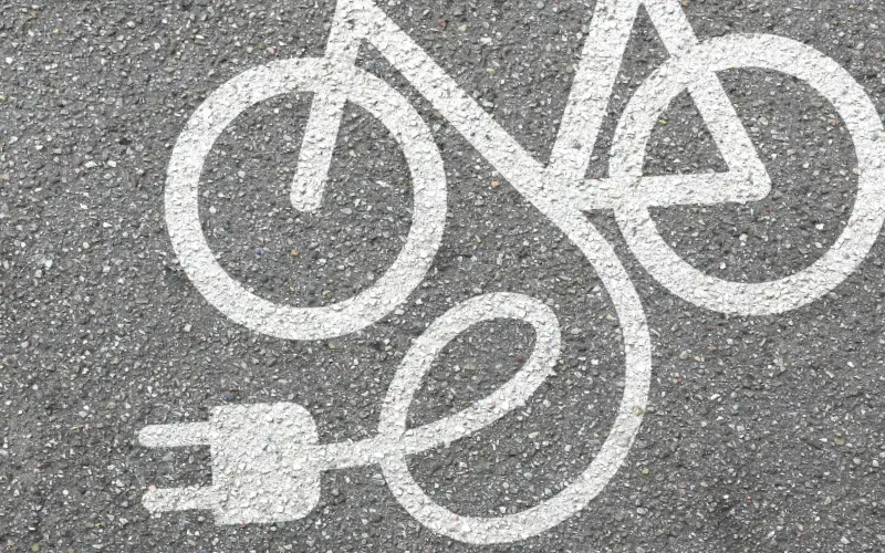 Símbolo pintado en el asfalto que representa una bicicleta eléctrica, con un enchufe al final del cuadro.