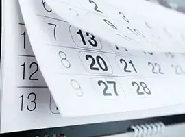Calendario impreso con hojas pasando, mostrando fechas resaltadas.