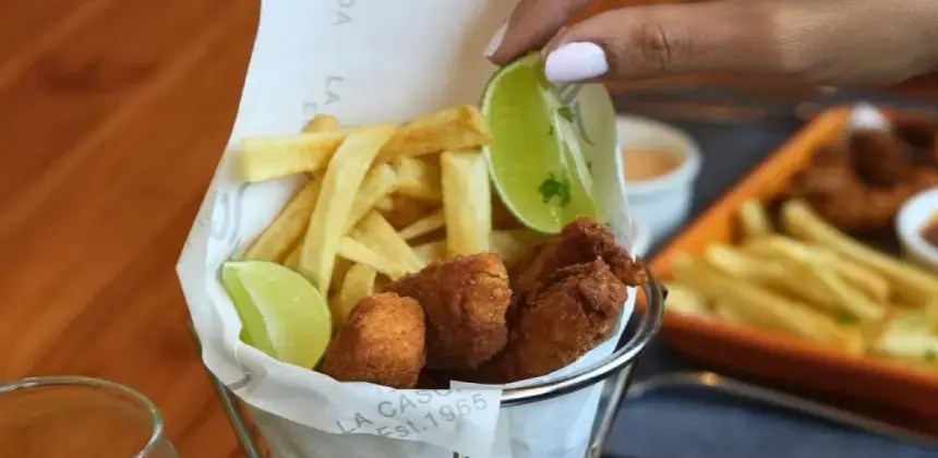 Canasta con trozos de pescado empanizado, papas fritas y rodajas de limón servida en restaurante