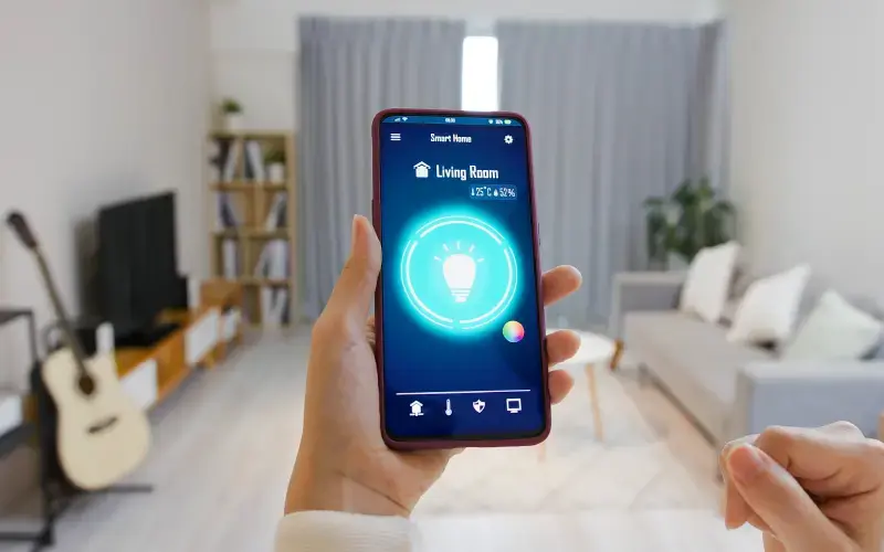 Persona controlando la iluminación del hogar desde una aplicación de casa inteligente en un teléfono móvil.