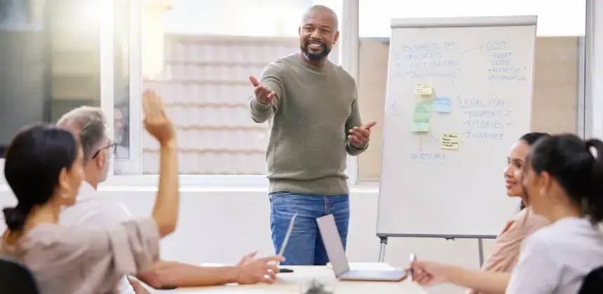 Instructor guiando una clase de formación profesional frente a grupo de estudiantes con pizarra en aula