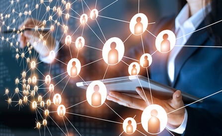 Mujer de negocios usando una tablet mientras interactúa con una red digital que conecta íconos de personas, simbolizando la conectividad y la transformación digital empresarial.