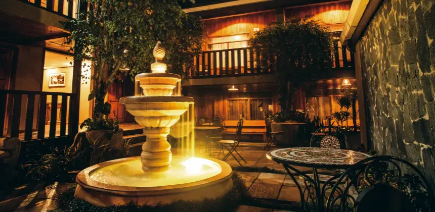 Patio interior del Country Lodge Monteverde con fuente iluminada y mesas rodeadas de vegetación