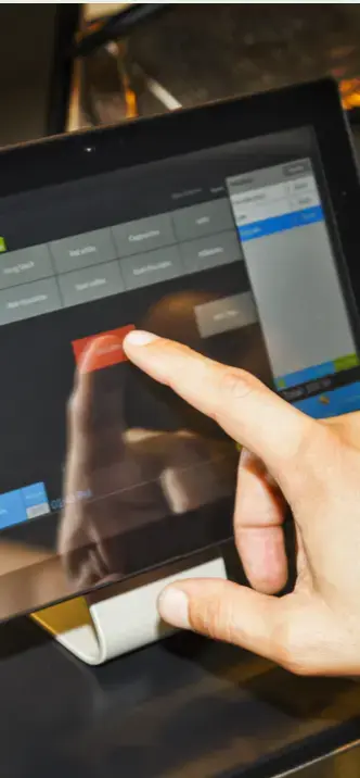 Persona utilizando una pantalla táctil de sistema punto de venta (POS) en una tienda o restaurante.
