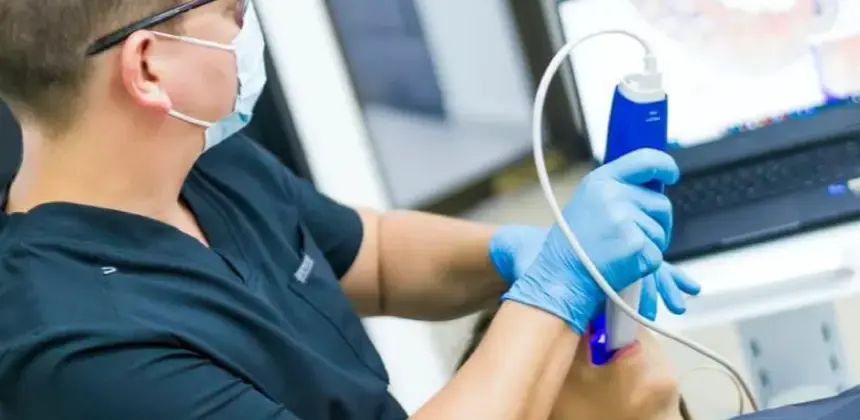 Dentista realizando escaneo digital en la boca de un paciente con equipo odontológico avanzado.