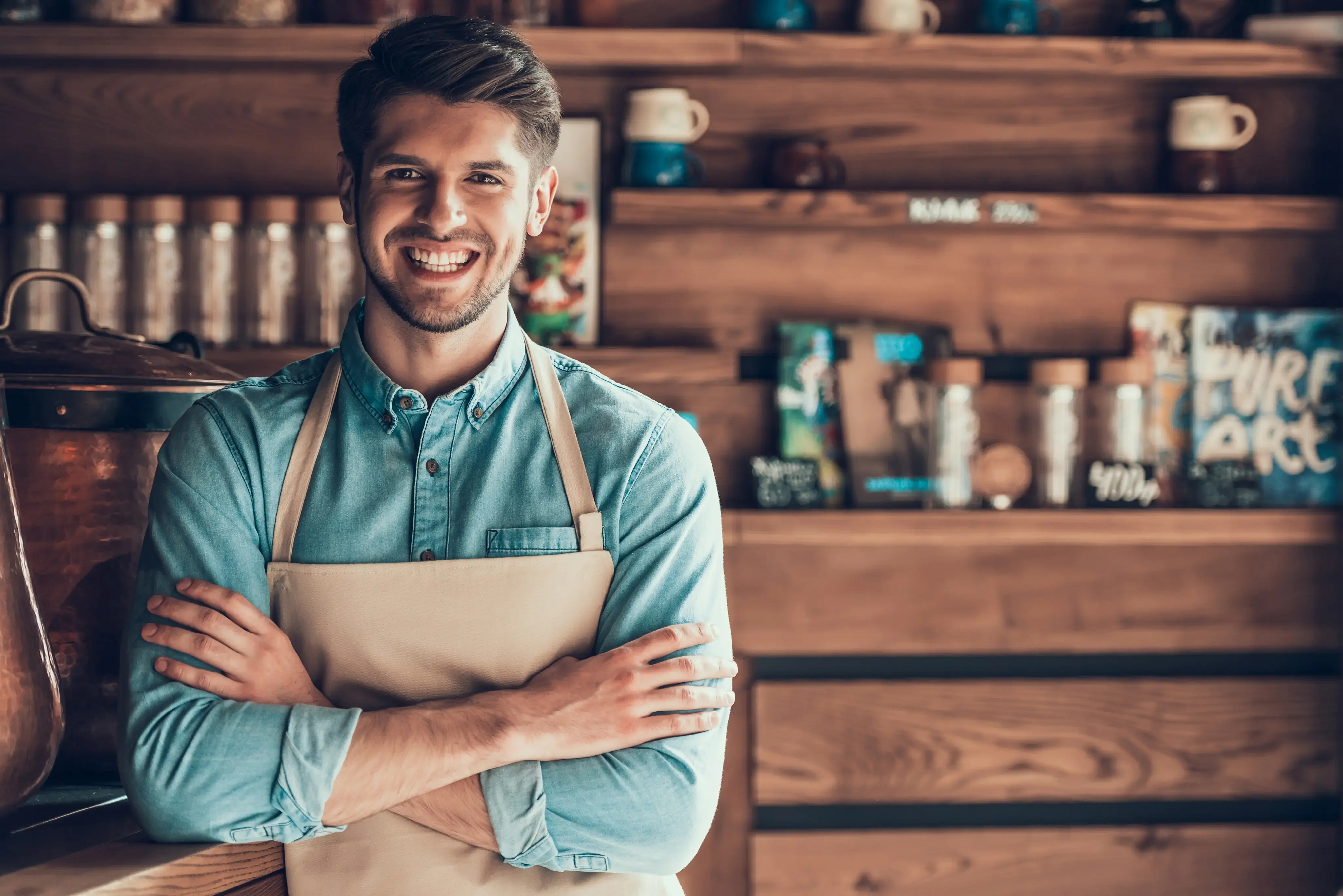 Hombre joven con delantal sonriendo dentro de un comercio.
