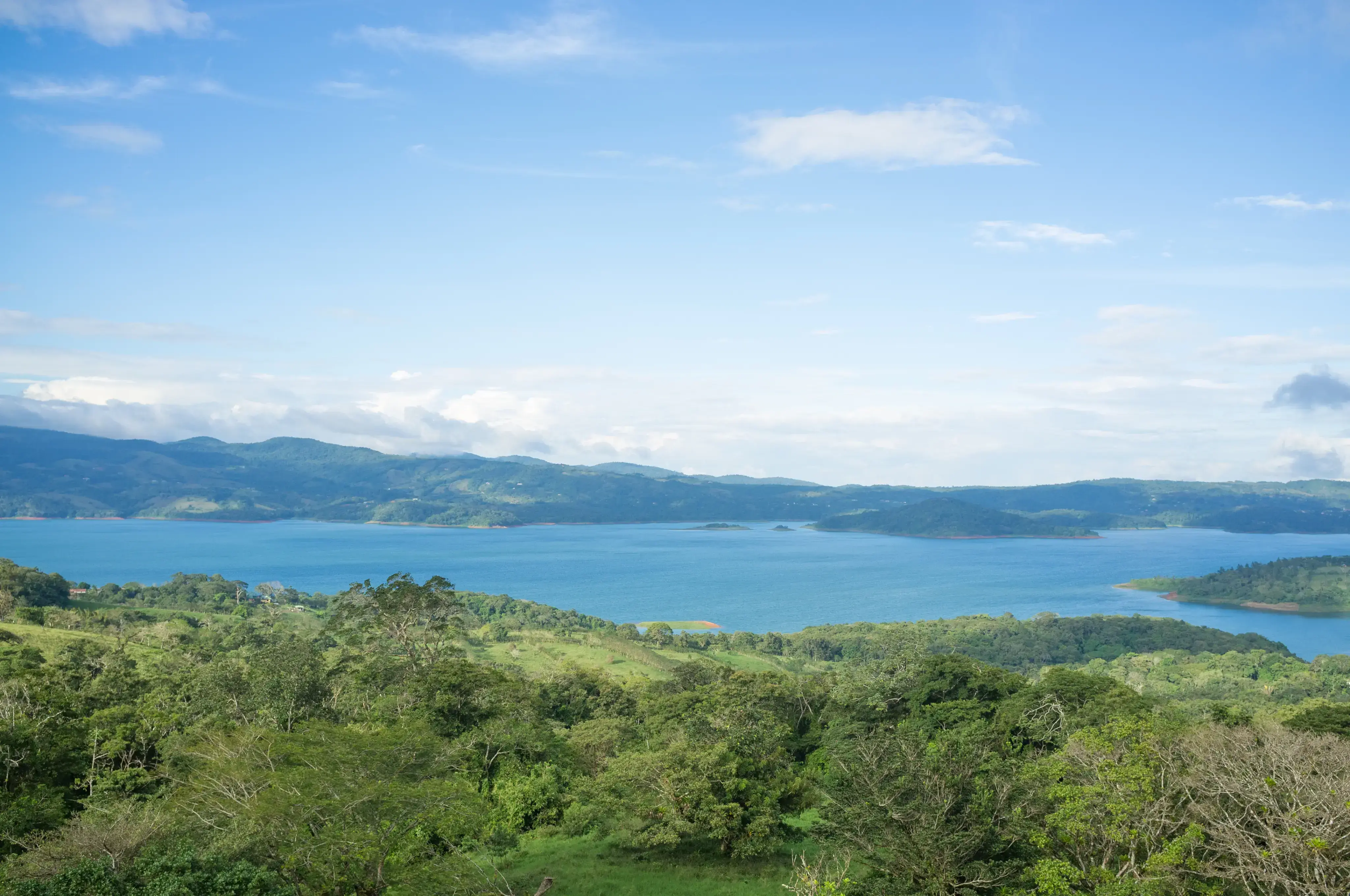 Vista panorámica de un lago rodeado de montañas y vegetación.