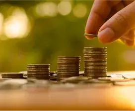 Mano apilando monedas, representando ahorro, inversión o crecimiento financiero.