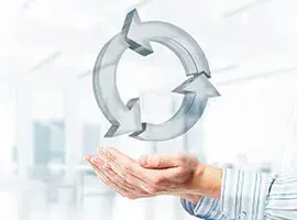 Mano sosteniendo símbolo de reciclaje o ciclo continuo hecho de flechas metálicas.