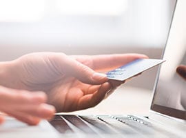 Mano insertando una tarjeta de crédito en una computadora portátil para realizar un pago.