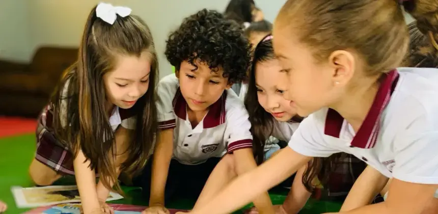 Niños en uniforme escolar realizando actividad grupal sobre una mesa en el aula